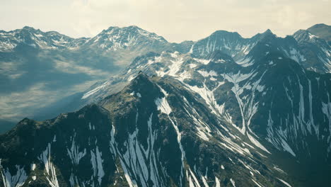 Aerial-Over-Valley-With-Snow-Capped-Mountains-In-Distance